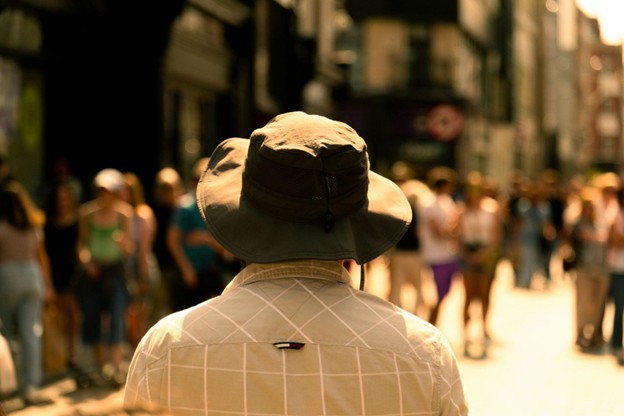 Man in a hat faces a crowded street.